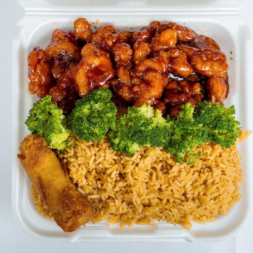 Kung Fu Wings' orange chicken with broccoli, fried rice, and an egg roll in a takeout container.