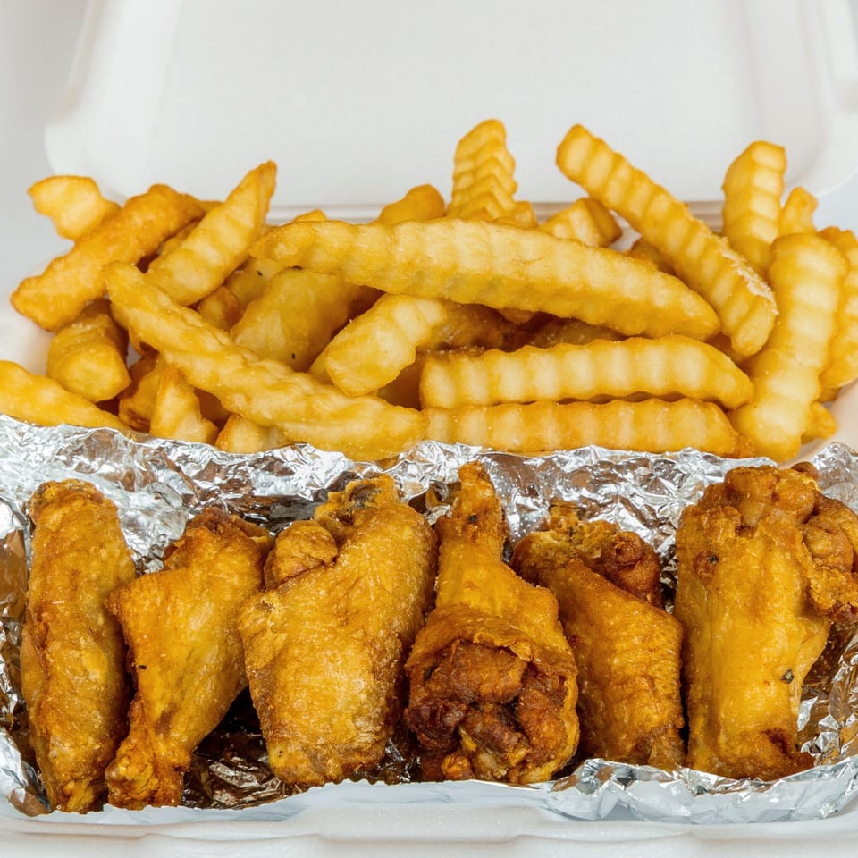 Crispy fried Kung Fu Wings and crinkle-cut fries in a white takeout container.